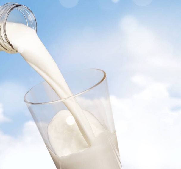 Glass jug of fresh milk on sky background - Zdjęcie, obraz
