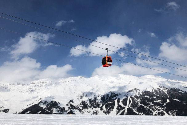 Cabine vermelha da cadeira de gôndola no fundo de um céu azul brilhante subir para o topo das montanhas. Actividades de Inverno. - Foto, Imagem