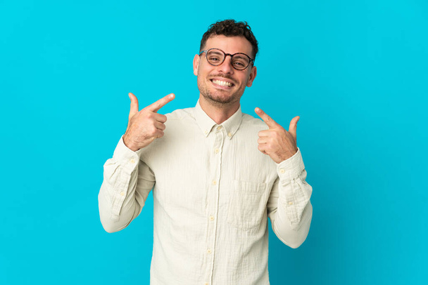 Young caucasian handsome man isolated on blue background giving a thumbs up gesture - Foto, Imagem