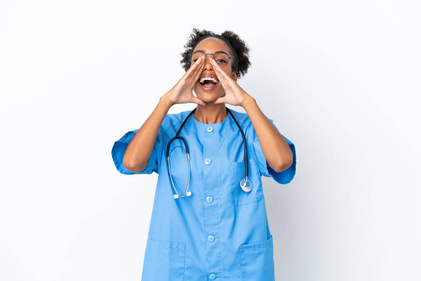 Mladý chirurg africký americký lékař žena izolované na bílém pozadí křičí a oznamuje něco - Fotografie, Obrázek