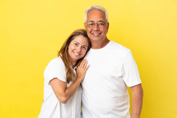 Ζευγάρι μέσης ηλικίας απομονωμένο σε κίτρινο φόντο γελώντας - Φωτογραφία, εικόνα