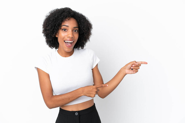 Молода афроамериканська жінка, ізольована на білому фоні, здивована і вказуючи на бік - Фото, зображення