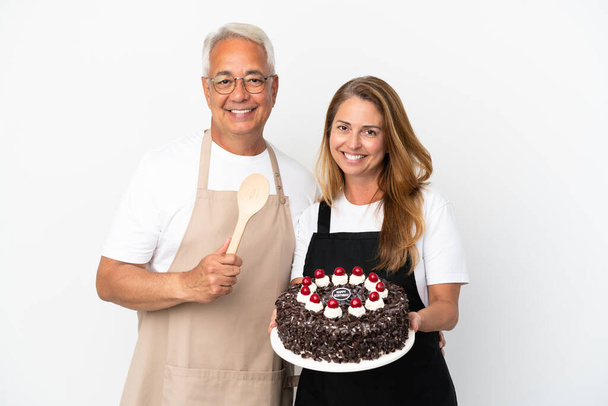 Middle age couple chef holding birthday cake isolated on white background - Foto, immagini