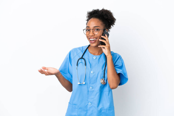 Young surgeon African American doctor woman isolated on white background keeping a conversation with the mobile phone with someone - Photo, Image