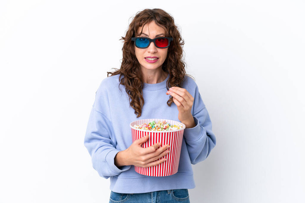 Young woman with curly hair isolated on white background with 3d glasses and holding a big bucket of popcorns - Fotoğraf, Görsel