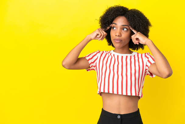 Young African American woman isolated on yellow background having doubts and thinking - Photo, Image