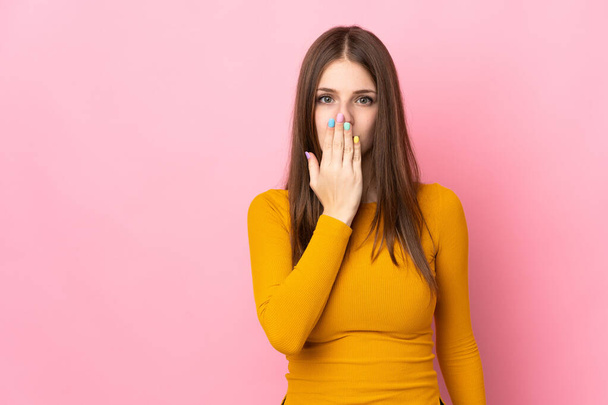 Mujer joven caucásica aislada sobre fondo rosa cubriendo la boca con la mano - Foto, imagen