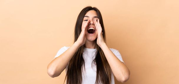 Teenager Brazilian girl over isolated background shouting and announcing something - Photo, Image
