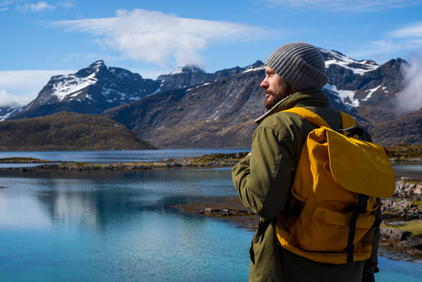 Guy viaja con una mochila amarilla a través de pintorescos lugares con hermosos paisajes de montaña. - Foto, imagen