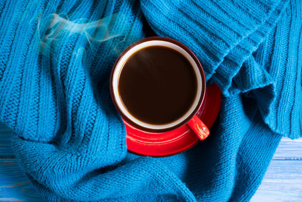 Ένα φλιτζάνι καφέ, ένα ζεστό κασκόλ σε ξύλινο φόντο - Φωτογραφία, εικόνα