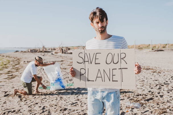 Skupina přátel aktivistů sbírajících plastový odpad na pláži. Lidi uklízejí na pláži, taškami. Koncepce ochrany životního prostředí a problémy znečištění oceánů - Fotografie, Obrázek