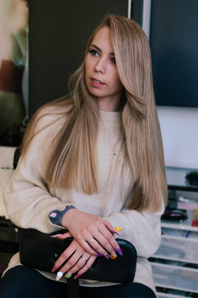 Blonde girl with beautiful long hair on a dark background indoors - Фото, зображення