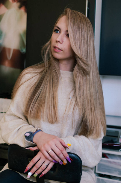 Blonde girl with beautiful long hair on a dark background indoors - Φωτογραφία, εικόνα