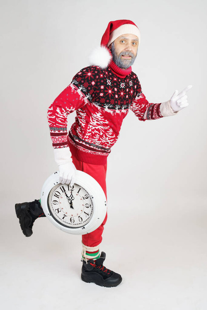 Christmas and New Year concept. Santa Claus holds a clock in his hands and runs. - Фото, зображення