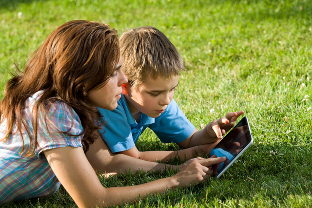 met behulp van laptop liggen op gras en gelukkige familie - Foto, afbeelding