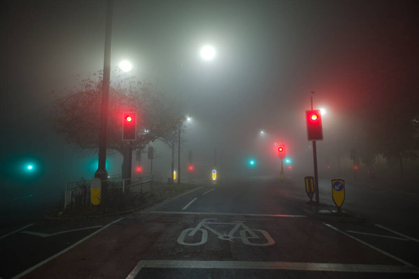 Цветные светофоры и белые фонари светят сквозь густой ночной туман на перекрестке рядом с больницей в Шеффилде.. - Фото, изображение