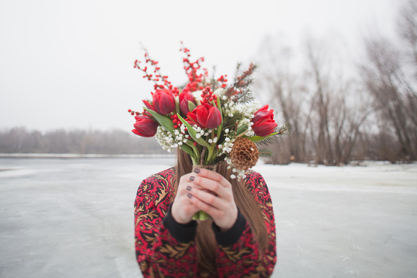 beautiful girl in the park in winter,  with a bouquet of red flo - Фото, изображение