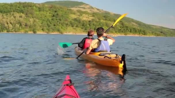 カップルの後に 2 番目のボートを湖でカヌー - 映像、動画