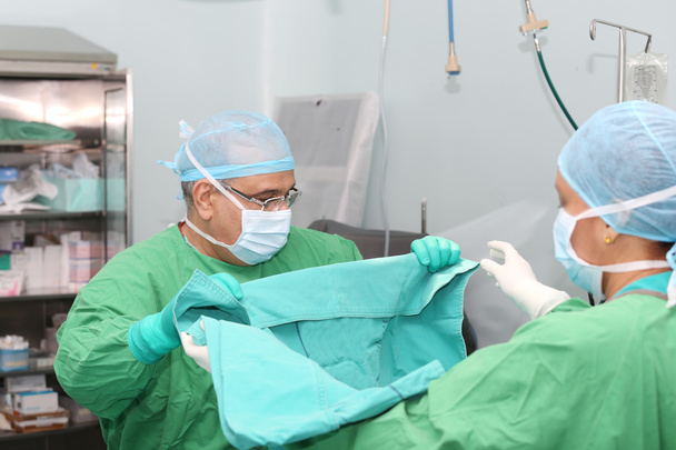 Médico y asistente doblando la manta para la cirugía
 - Foto, Imagen