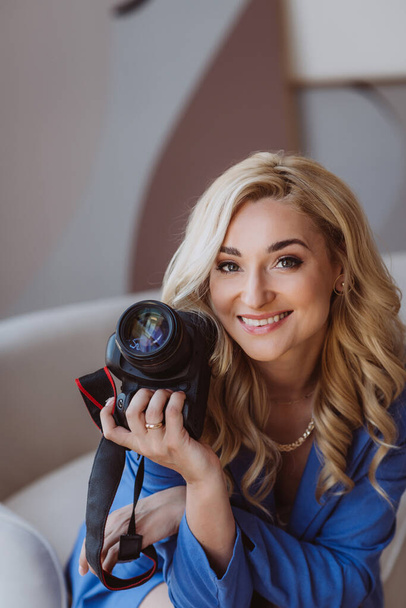 Beautiful woman freelancer, blogger, influencer with a camera in her hands. Photographer, hobby profession. Soft selective focus. - Foto, afbeelding