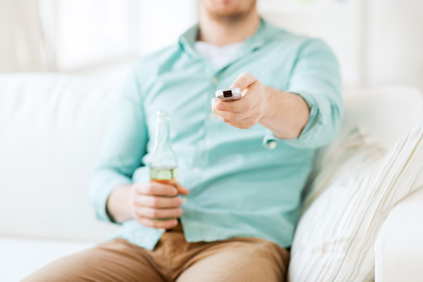 man with beer and remote control at home - Foto, Bild