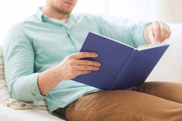 close up of man reading book at home - Foto, Imagen