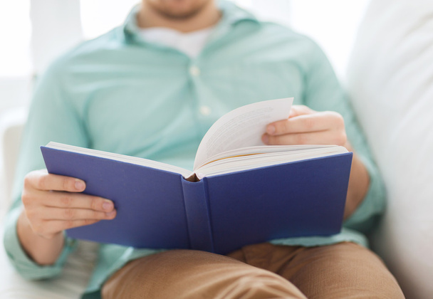 close up of man reading book at home - Foto, Bild