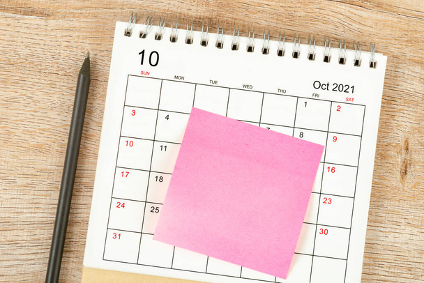 Widok z góry długopisu, planowanie kalendarza i termin z lepką notatką na drewnianym tle, Kalendarz 2021 na październik miesiąc - Zdjęcie, obraz
