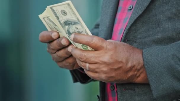 Vágott szemű afrikai férfi egy halom dollárral számolja a pénzt. A férfi kezek közelsége készpénznek számít. Fizetésfizetés. Sikeres üzlet, magas jövedelmű koncepció. Amerikai valutaváltás a bankban - Felvétel, videó