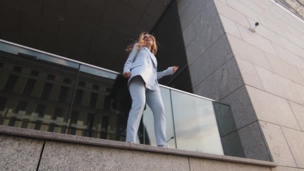 Bottom view funny caucasian successful business woman student girl in stylish suit manager worker stands on balcony terrace near office building of company dancing dance actively moving having fun - Footage, Video