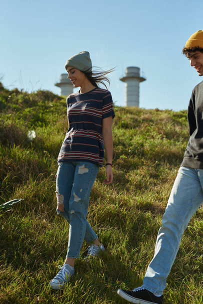 Two cheery young people walking down a hill with the wing blowing through their hair - Valokuva, kuva