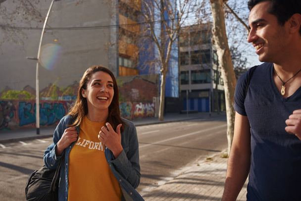 Young woman in a yellow t shirt smiles at the young man walking beside her - Φωτογραφία, εικόνα
