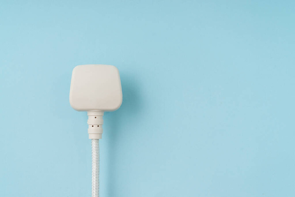 Three pin plug on light blue background with a copy space. - Foto, Imagen