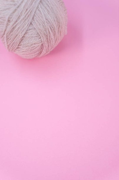 A vertical shot of isolated beige yarn on a pink background with text space - Φωτογραφία, εικόνα