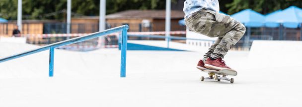 στενή επάνω του ένα skateboarders πόδια ενώ πατινάζ στο σκυρόδεμα στο skate park - Φωτογραφία, εικόνα