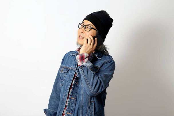 The Asian man with denim shirt and beanie standing on the white background. - Fotó, kép