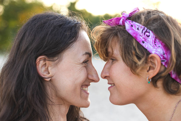 Egy cuki leszbikus pár portréja. A két lány egymásra néz. Szerelem és hozzáállás. LMBT-koncepció - Fotó, kép