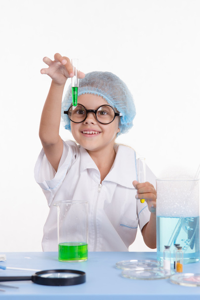 Wissenschaftlermädchen blickt glücklich auf Reagenzglas mit Flüssigkeit - Foto, Bild