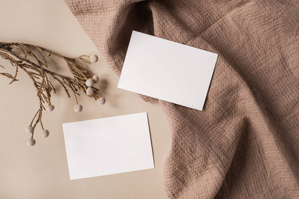 Carte de feuille de papier vierge avec espace de copie maquette et branche florale sèche et tissu couverture sur fond beige neutre. Modèle de marque d'entreprise esthétique minimale. Couché plat, vue du dessus - Photo, image