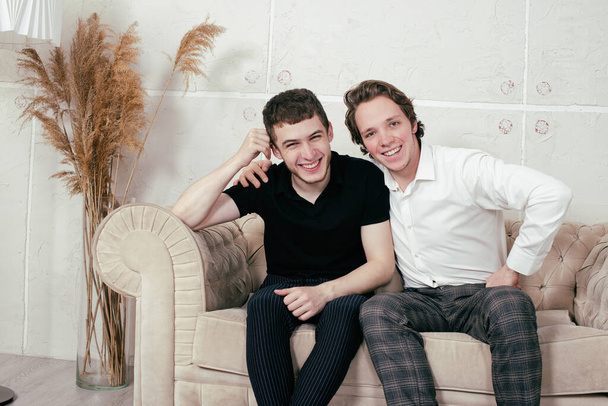 Young happy gay couple relaxing at home and watching the news. - Photo, Image