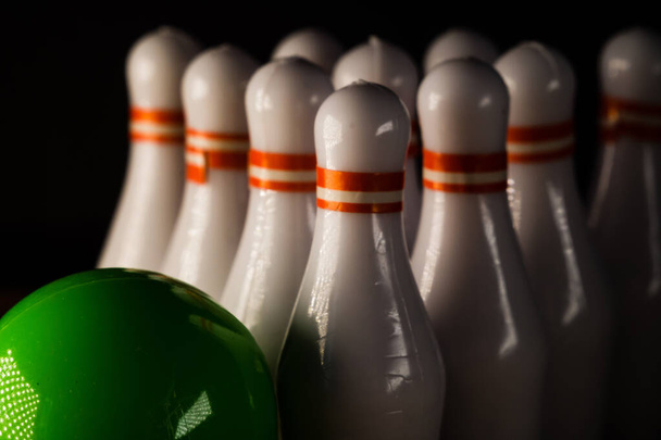 A green ball and bowling pins on a wooden plank - Foto, afbeelding