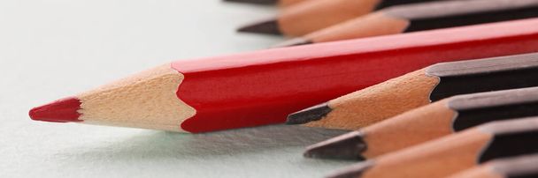 Rood scherp houten potlood liggend voorbij zwart closeup achtergrond - Foto, afbeelding