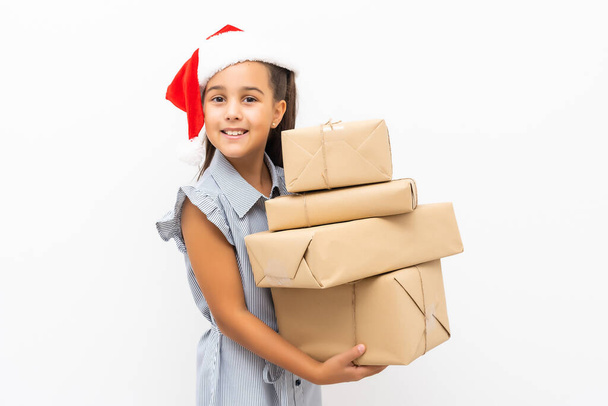 Young child holding large stack of Christmas presents wearing a Santa hat isolated on white - Foto, Imagen