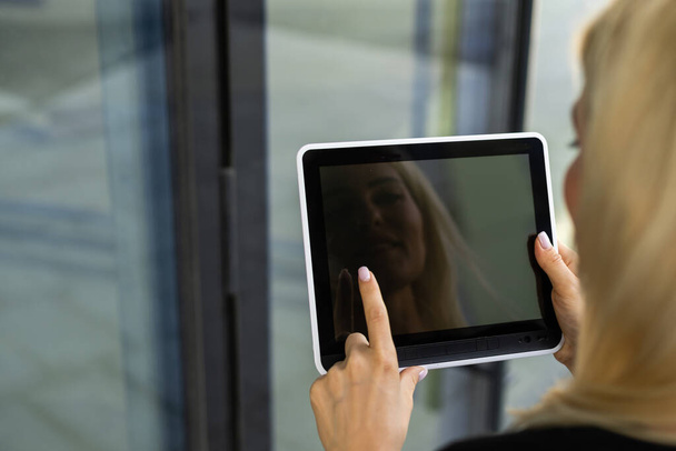 Portrait of a successful woman using digital tablet during quick break in front a corporate building. - Fotó, kép