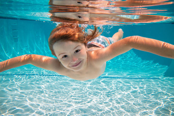 Funny face portrait of child boy swimming and diving underwater with fun in pool. Kid in the water swimming underwater and smiling. Children swim underwater. Funny kids face. - Zdjęcie, obraz