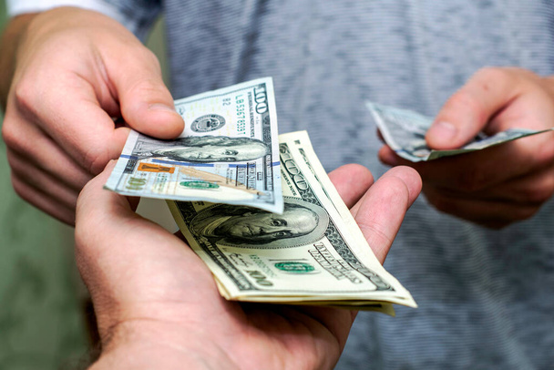 una persona passa un altro un fascio di banconote da cento dollari contandoli. Foto di alta qualità - Foto, immagini