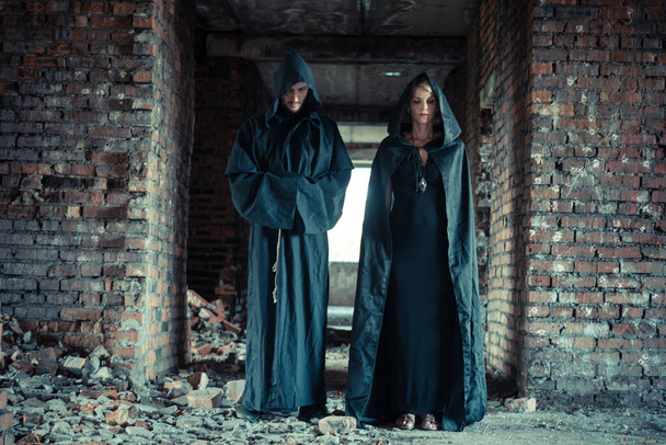 a man and a woman in black cloaks, two sorcerers in the ruins - Photo, Image