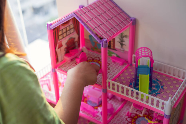 Casa de muñecas rosa con un niño jugando con ella. - Foto, imagen