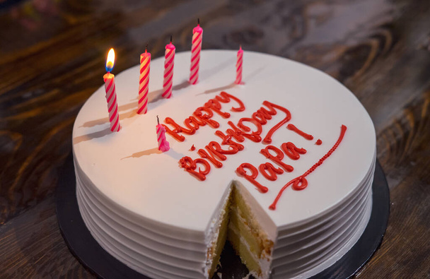 Syntymäpäiväkakku isälle kirjoitti pöydälle "Hyvää syntymäpäivää isä". Valaistus kynttilä kakku. - Valokuva, kuva