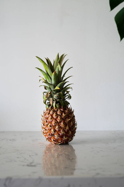 single whole pineapple on white wall and marble table background - Foto, Imagen